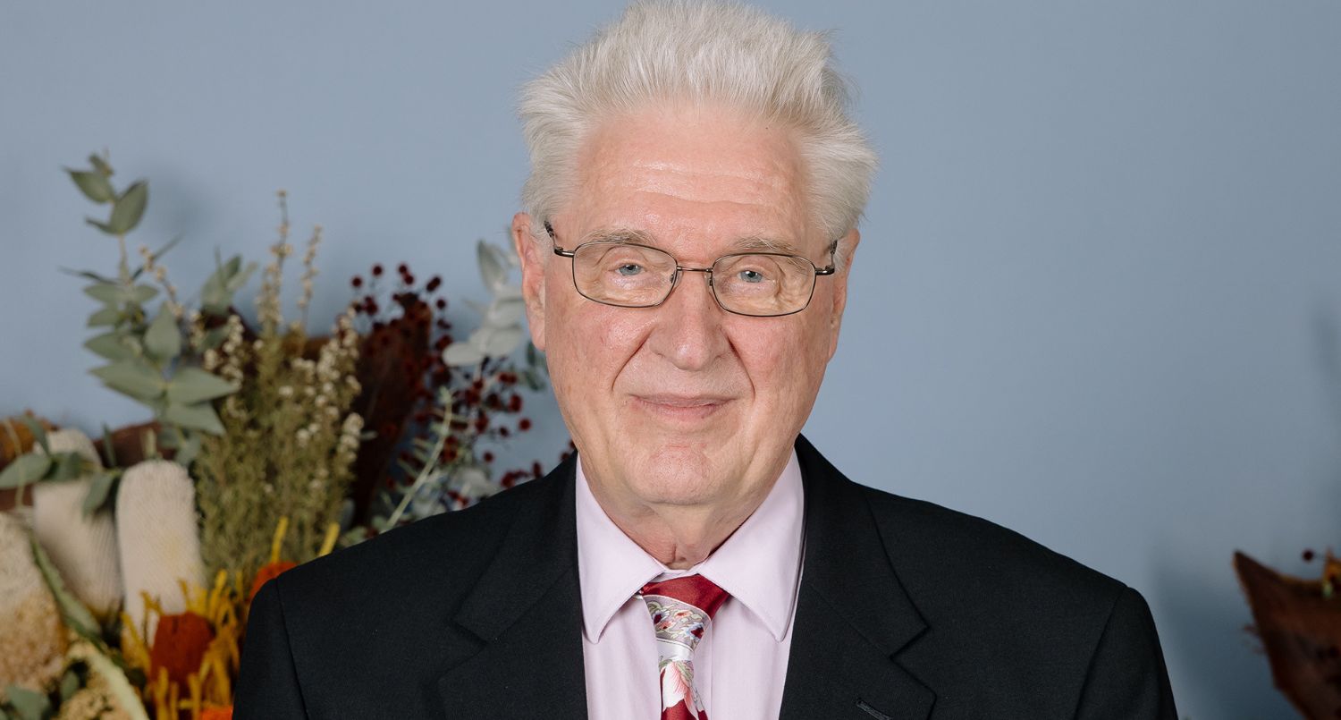 A white haired man, wearing glasses.