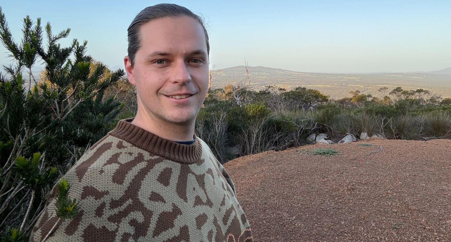 A person wearing knitted jumper, standing outdoors.