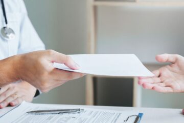 A patient receiving a piece of paper from a doctor.