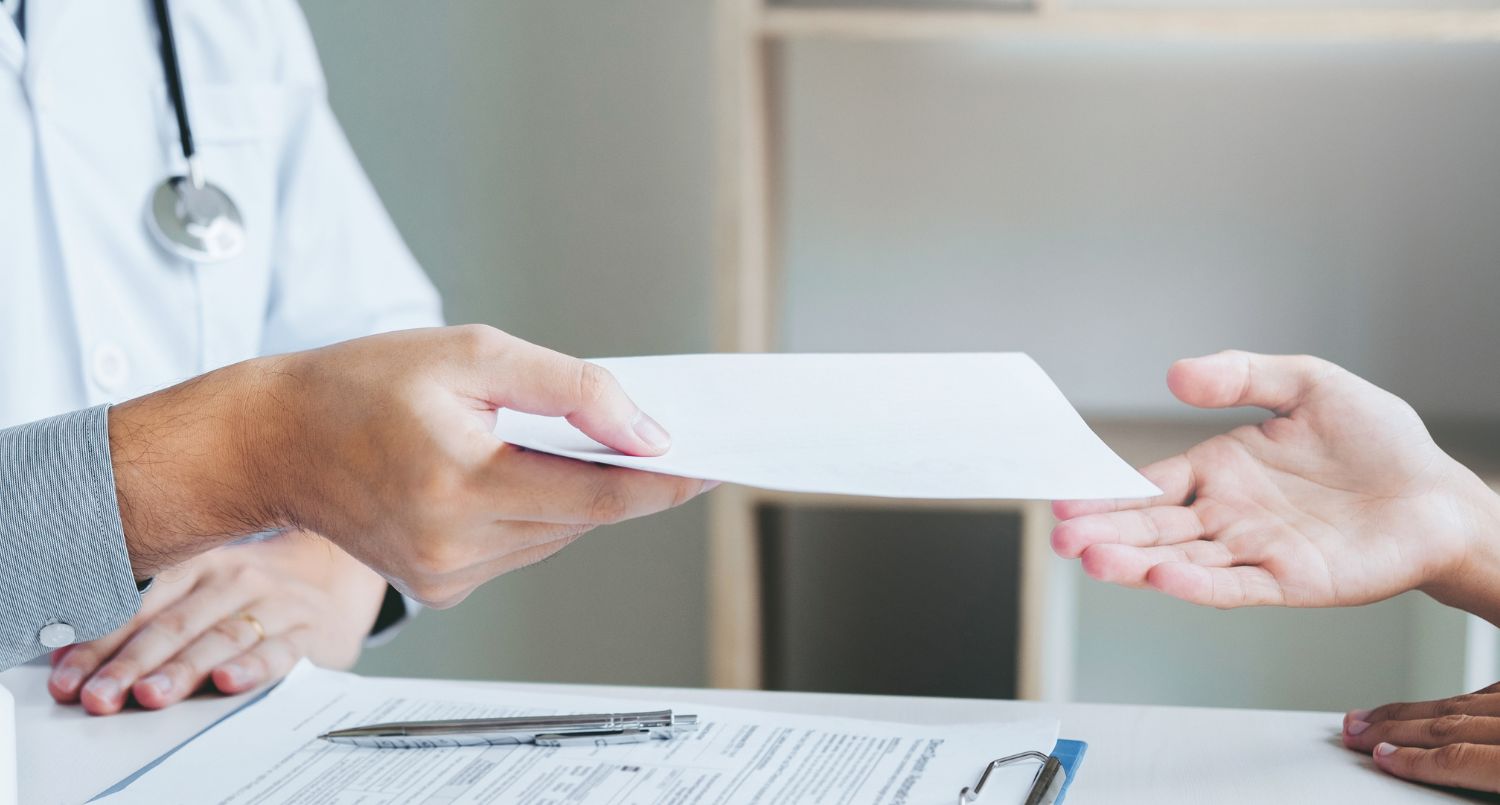 A patient receiving a piece of paper from a doctor.