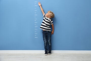 A child pointing to lines on the wall.