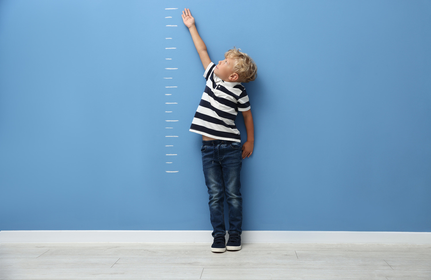 A child pointing to lines on the wall.